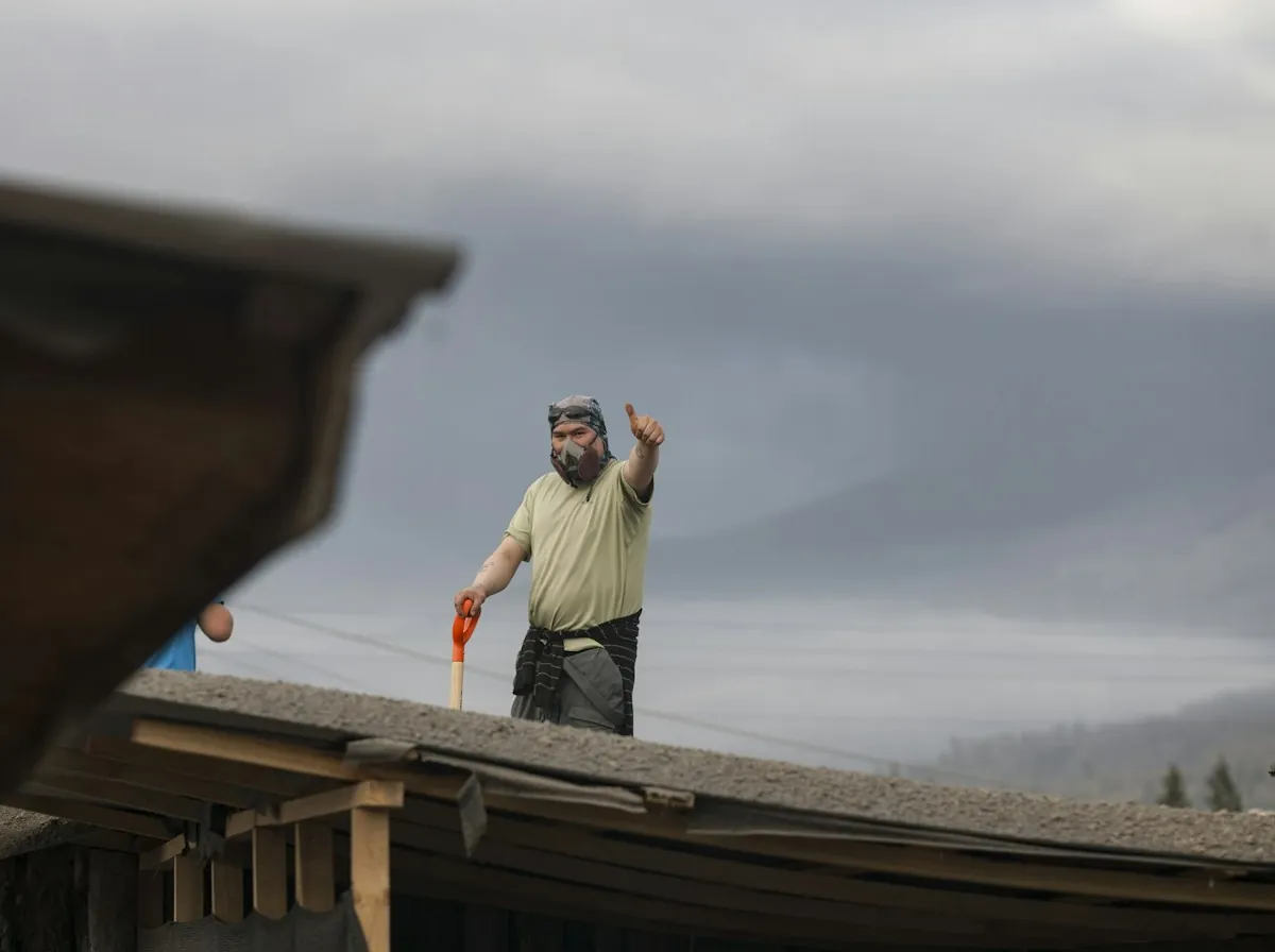 Roof Replacement in Sherman — a roofer standing on a low-pitch roof giving a thumbs-up